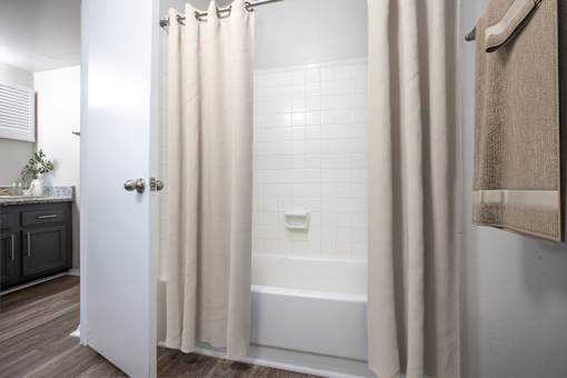 A white bathroom with a white tub and a white shower curtain.