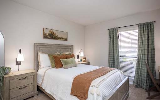A bedroom with a large bed, a nightstand with a lamp, and a painting on the wall.