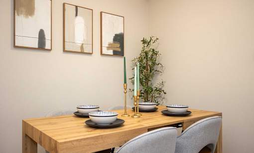 A dining table with chairs, bowls, and a vase with a plant.