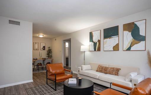 A living room with a white couch, orange chairs, and a black coffee table.