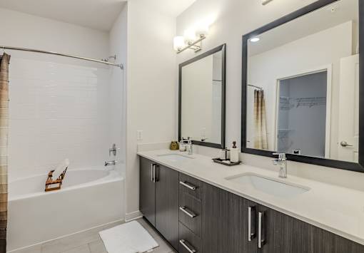 A modern bathroom with a white tub, sink, and mirror.