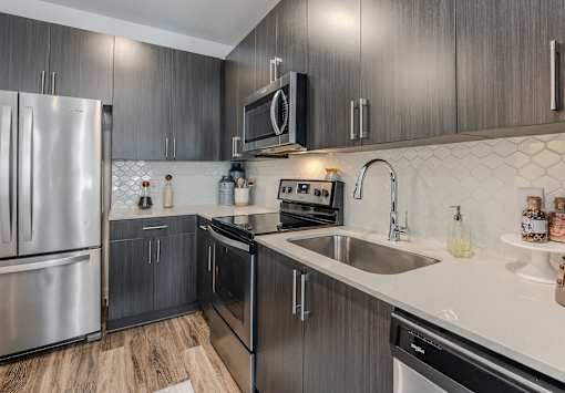 A modern kitchen with dark wood cabinets and stainless steel appliances.