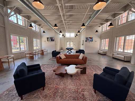 A large room with a rug and several chairs.