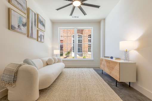 A living room with a white couch and a ceiling fan.