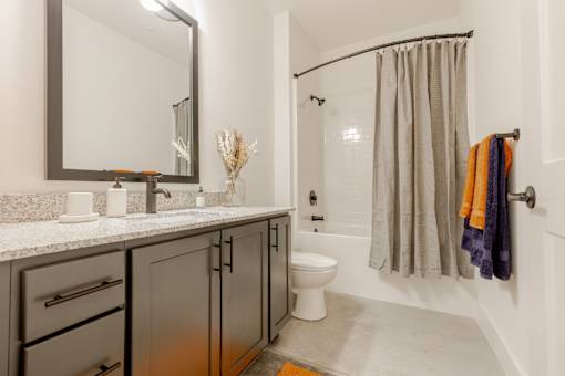 A bathroom with a sink, mirror, toilet, and shower.