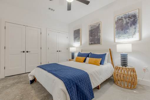 A bedroom with a bed, a ceiling fan, and a wicker stool.