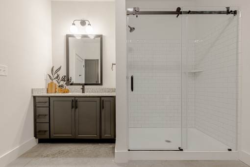 A bathroom with a mirror, vanity, and shower.