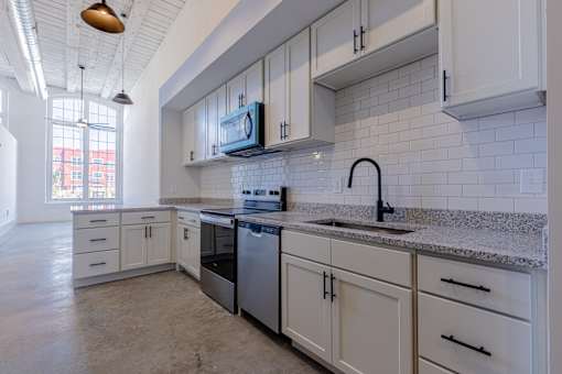 A kitchen with white cabinets and a granite countertop.