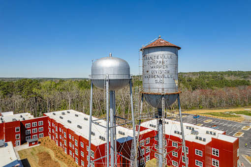 Two large water towers are situated in front of a red brick building.