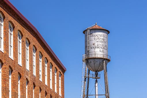 A water tower stands next to a brick building.