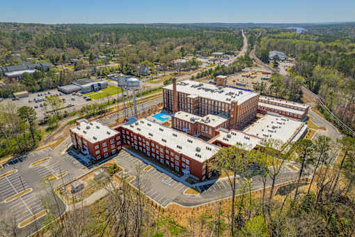 A large red building with a pool in the middle surrounded by a parking lot.