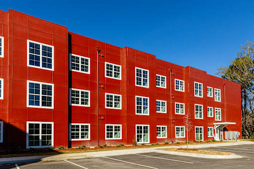A red building with a parking lot in front.