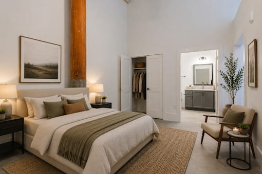 A bedroom with a large bed and a chair.