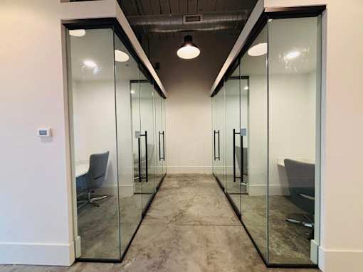 A hallway with glass walls and a grey chair.