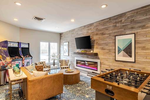 A room with a foosball table, couches, and a television.