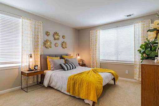 A bedroom with a bed, nightstands, and a window with white blinds.