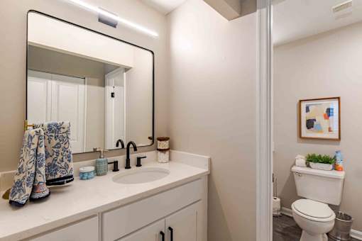 A bathroom with a white toilet and a mirror above a sink.