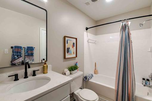 A bathroom with a white sink, toilet, and a striped shower curtain.