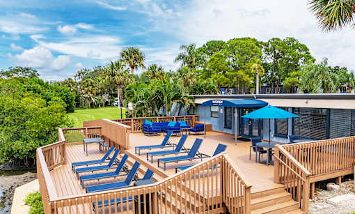 A wooden deck with blue lounge chairs and a blue umbrella at Waterview at Rocky Point, Tampa, FL