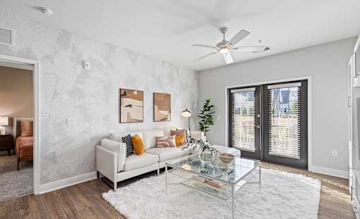 A living room with a white couch and a glass coffee table.