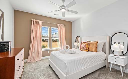 A bedroom with a large bed, a dresser, and a ceiling fan.