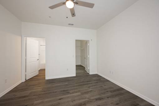 A room with a ceiling fan and wooden flooring.