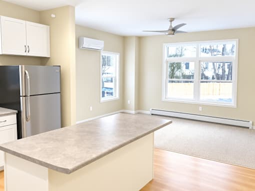 A kitchen with a refrigerator, a counter, and a window.