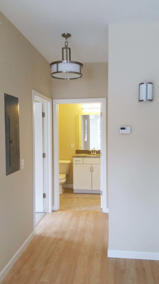 Hayes hallway with wood floors leading to full bathroom