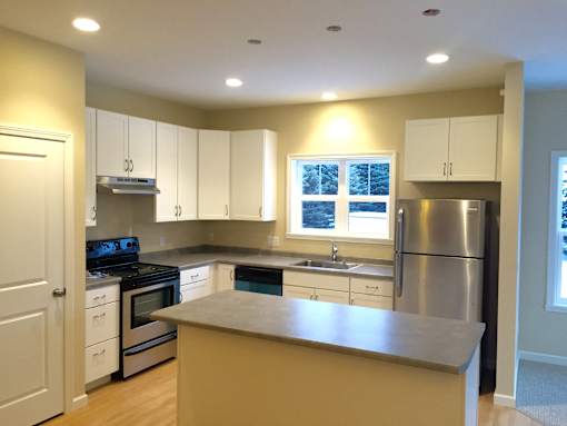 Hayes kitchen featuring stainless steal refrigerator and stove, kitchen island and wood floors