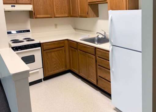 Country Park kitchen with refrigerator, stove and upper and lower storage cabinets