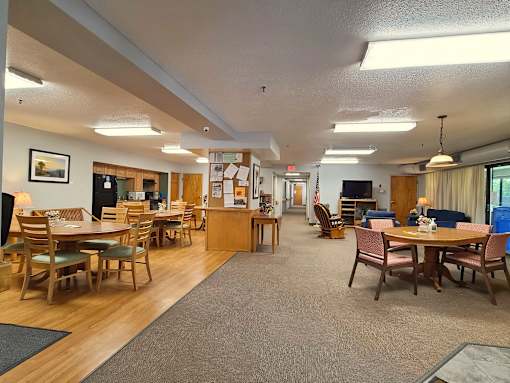 McKenzie House community room with tables, television and comfy chairs