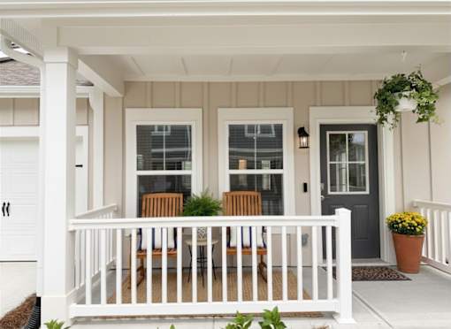 A white porch with a table and chairs.