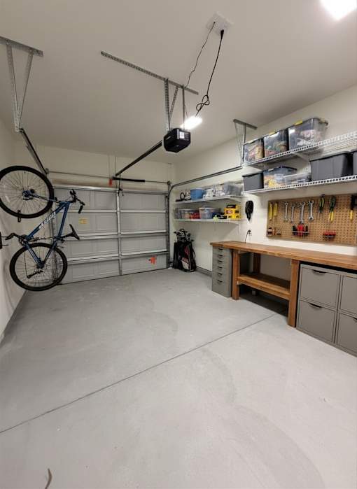 A garage with a bicycle hanging from the ceiling and a workbench with tools on it.