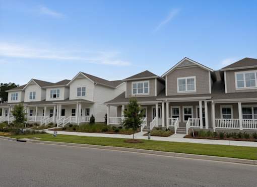 A row of houses with white front porches and brown roofs.
