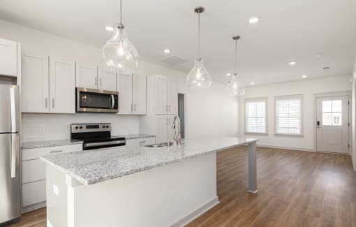 a kitchen with white cabinets and a marble counter top