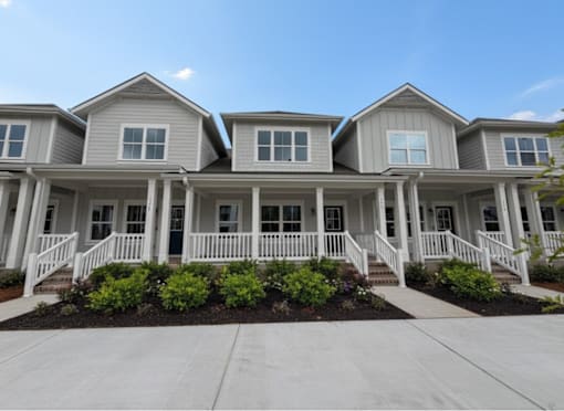 A row of houses with white railings and steps leading to the front doors.