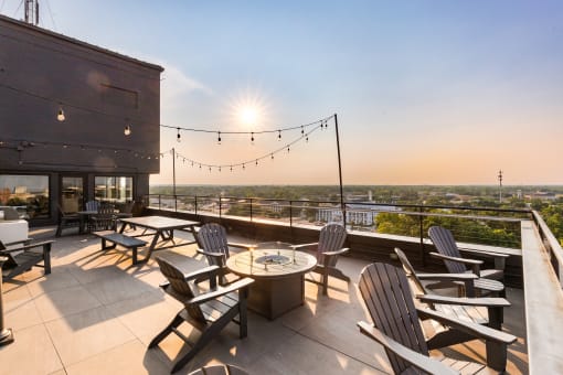 a roof deck with chairs and a fire pit overlooking the city