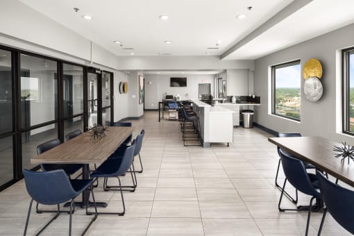 a communal area with tables and chairs and a kitchen in the background