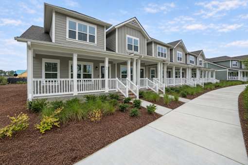 A series of houses with white railings and steps leading to the front door.