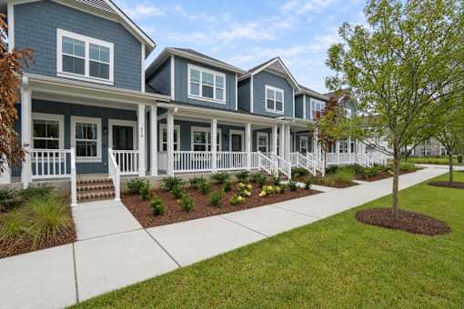 A row of houses with white railings and a tree in the front yard.
