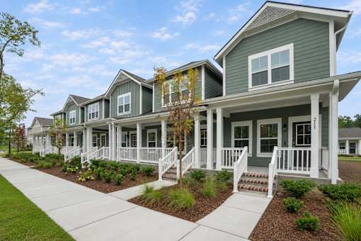 A row of houses with green siding and white trim.