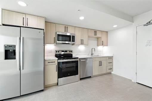 A modern kitchen with a refrigerator, microwave, oven, and sink.