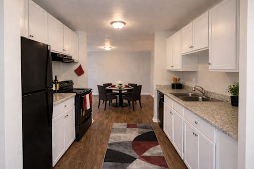 A kitchen with black appliances and white cabinets.