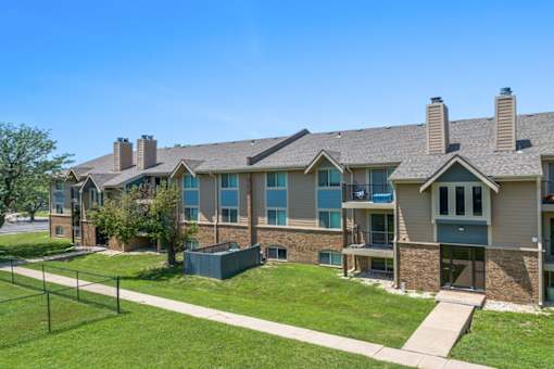 the view of an apartment building with a lawn and a fence