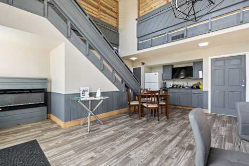 a living room with a table and chairs and a kitchen with a staircase