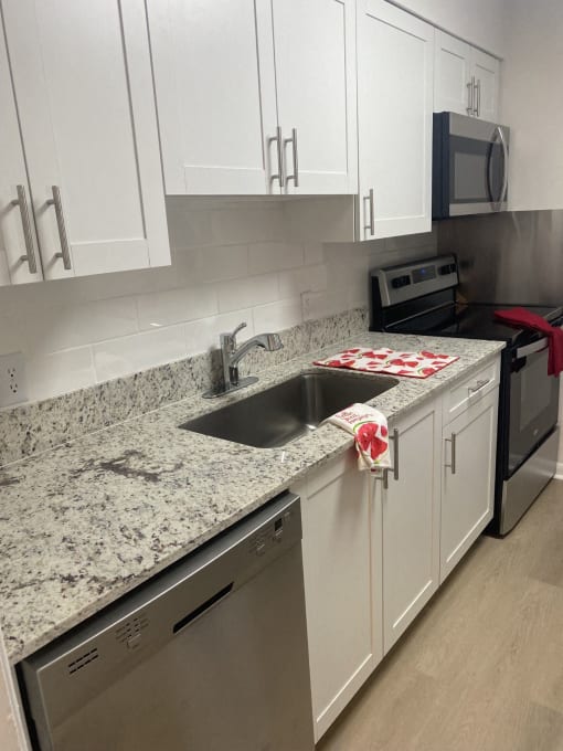 a kitchen with white cabinets and granite counter tops and a sink
