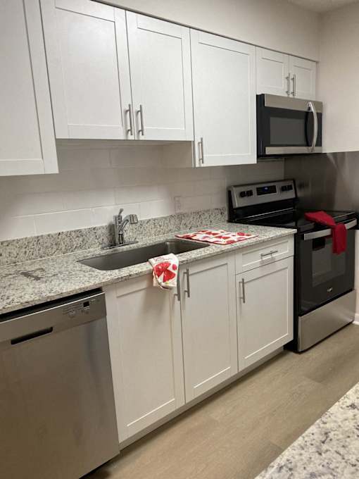 a kitchen with white cabinets and black appliances and granite counter tops