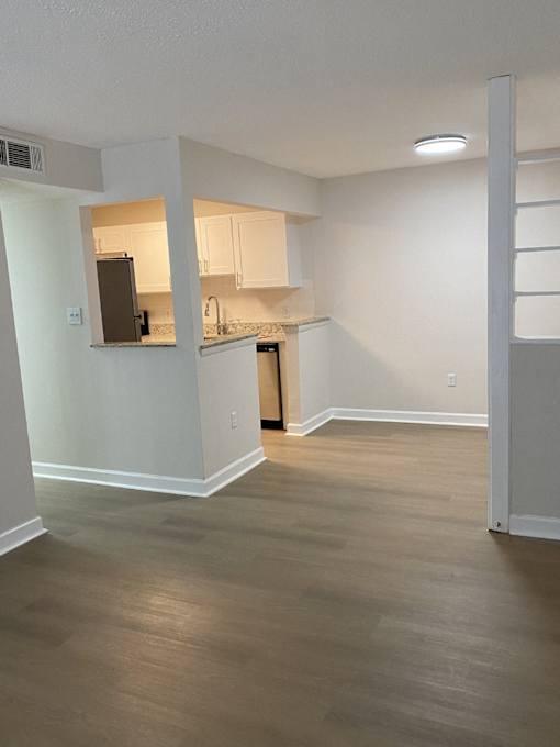 an empty living room and kitchen with wood flooring