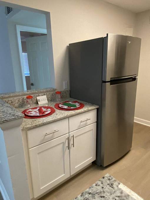 a kitchen with white cabinets and a stainless steel refrigerator