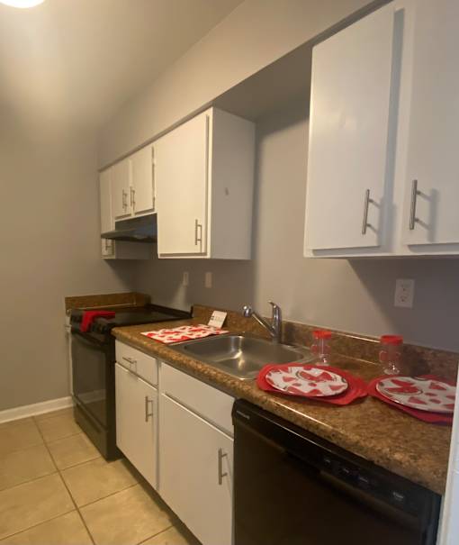A kitchen with white cabinets and a black dishwasher.